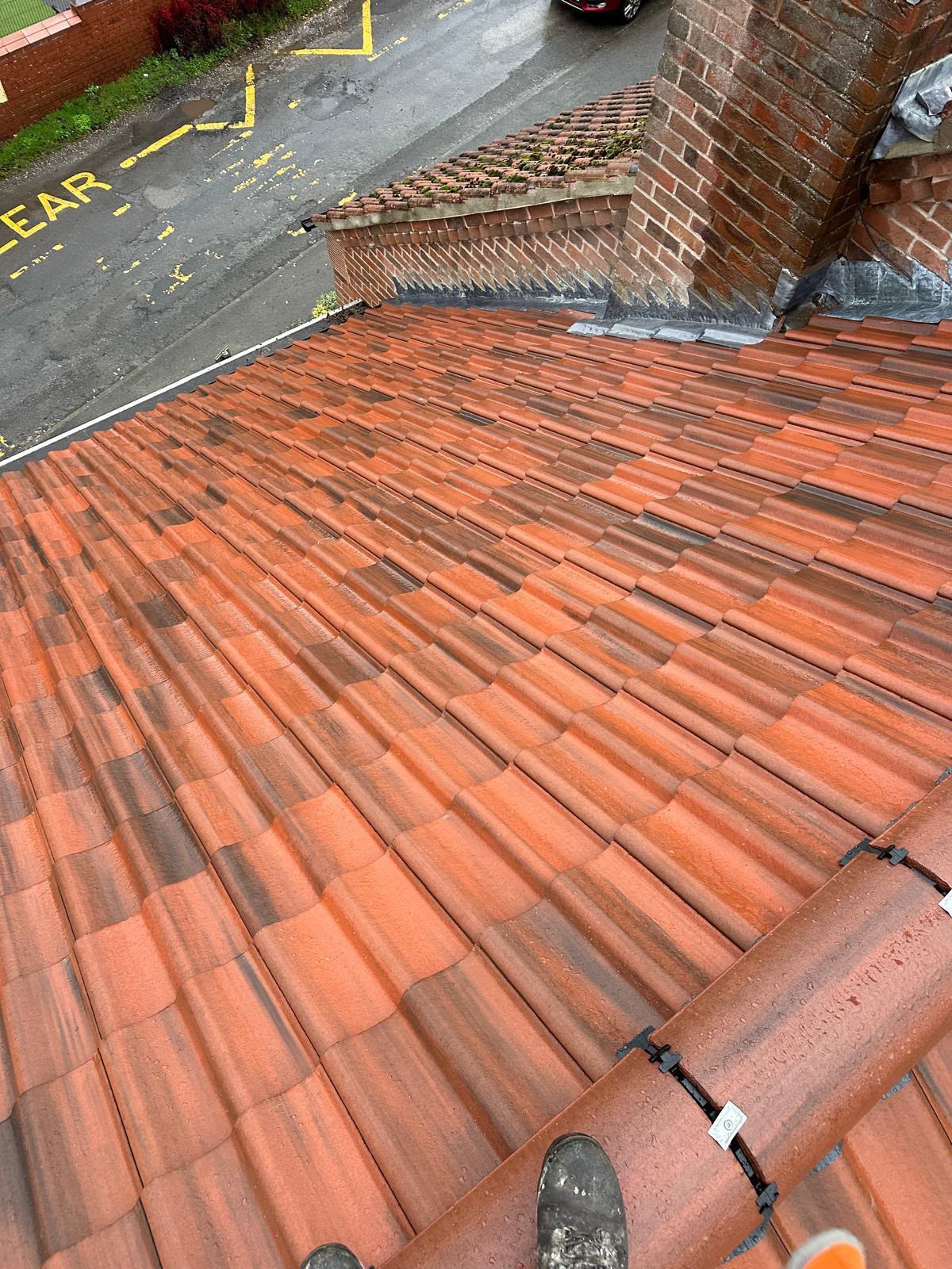 New red tiled roof with hand-dressed lead flashing around a brick chimney