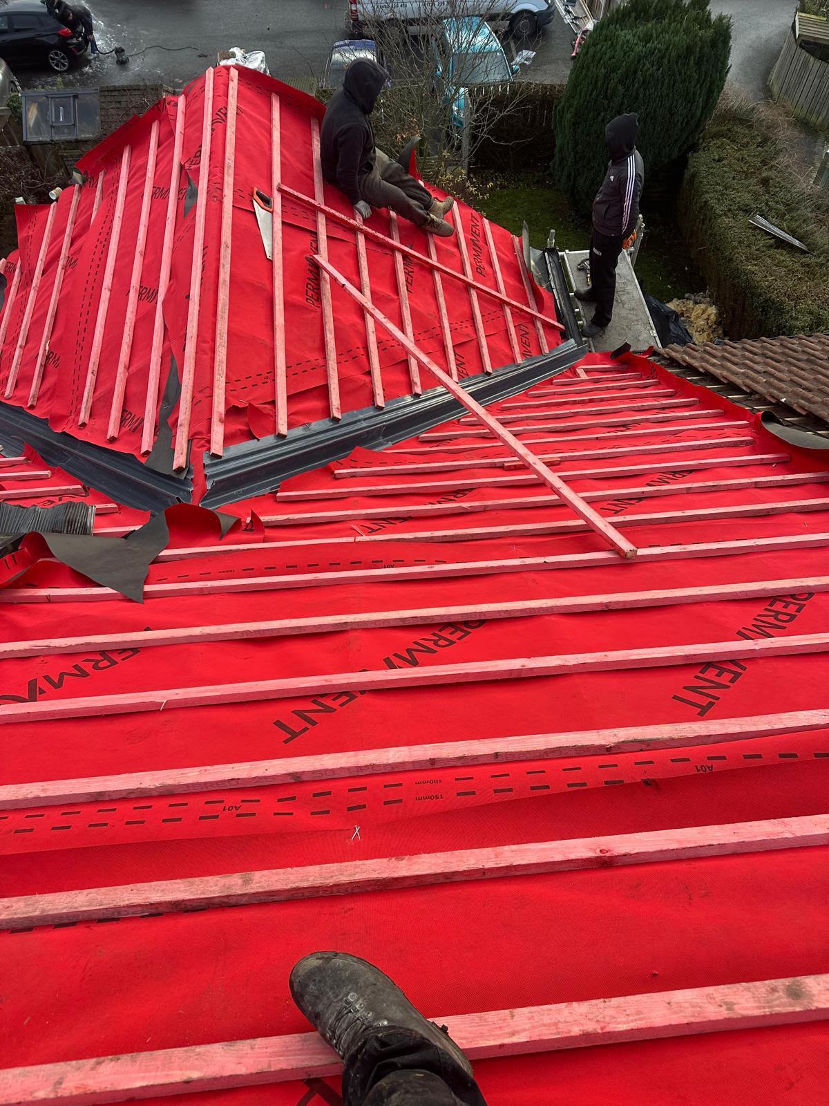 Red breathable membrane and battens dressed around a roof valley and hip mid-project